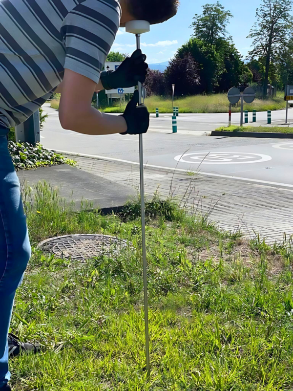 Geófono GEO-001 en uso, con trompeta de escucha para la detección precisa de fugas en tuberías de agua. El palo de acero inoxidable desmontable de 1 metro (ampliable a 1,5 metros) cuenta con elementos mecánicos de amplificación para mejorar la detección y un casquillo de nylon ergonómico para amplificar el sonido. Ideal para profesionales y usuarios domésticos.